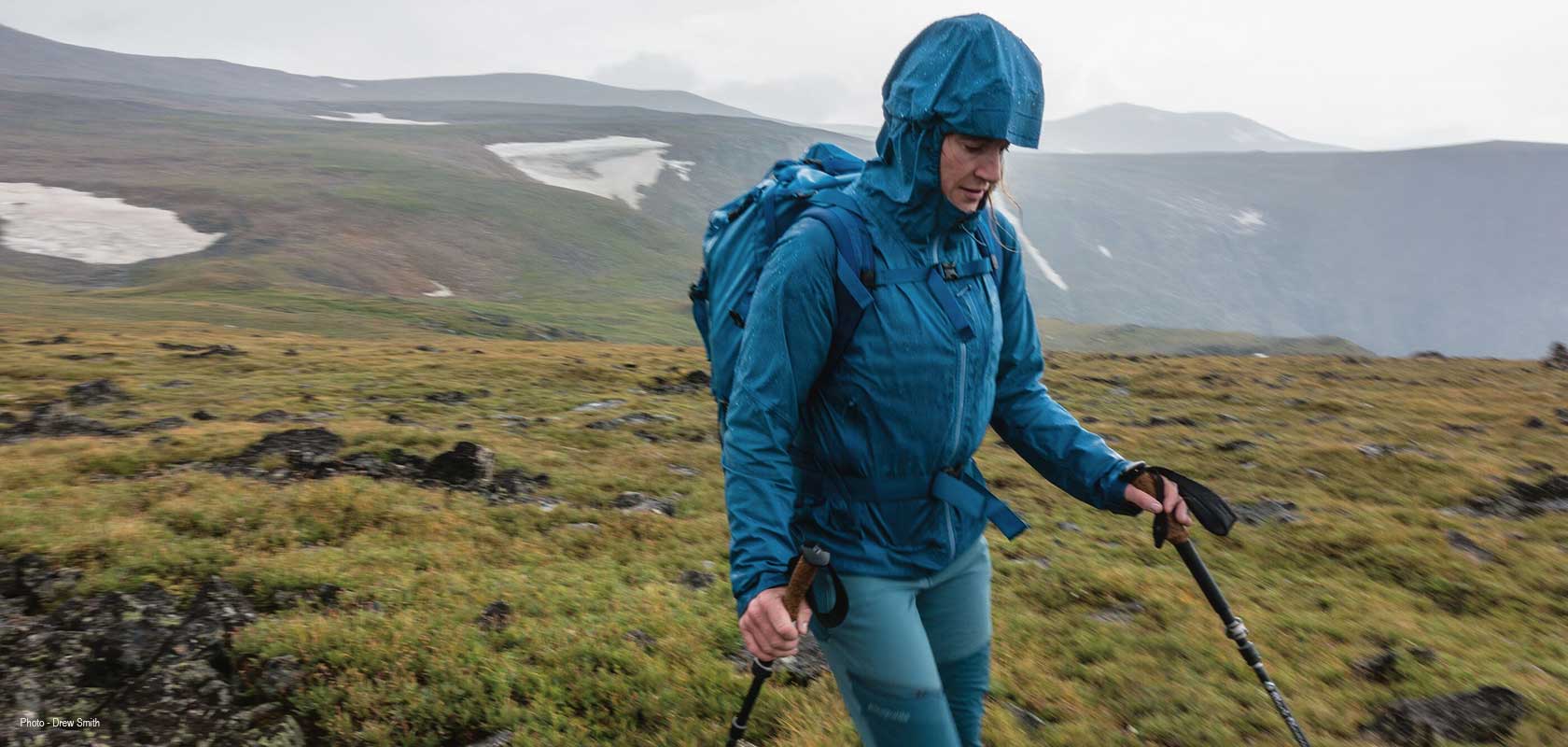 A person is hiking with trekking poles, wearing Patagonia clothes.