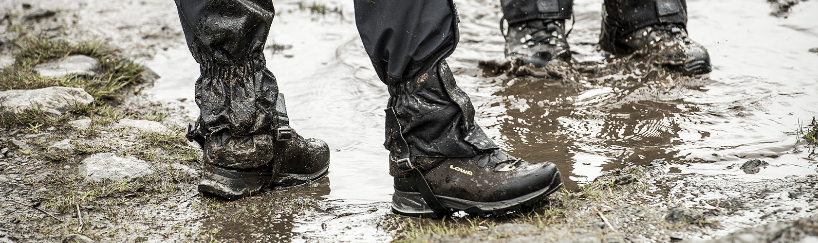 An image of people wearing their walking boots in a muddy puddle