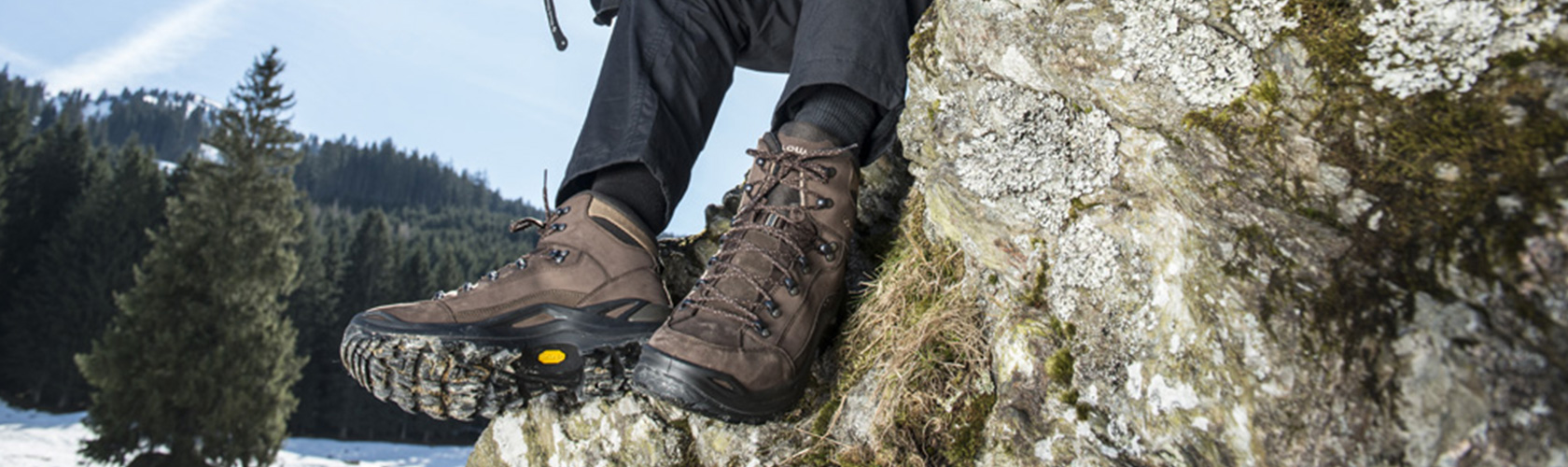 A person sat on a rock wearing walking boots
