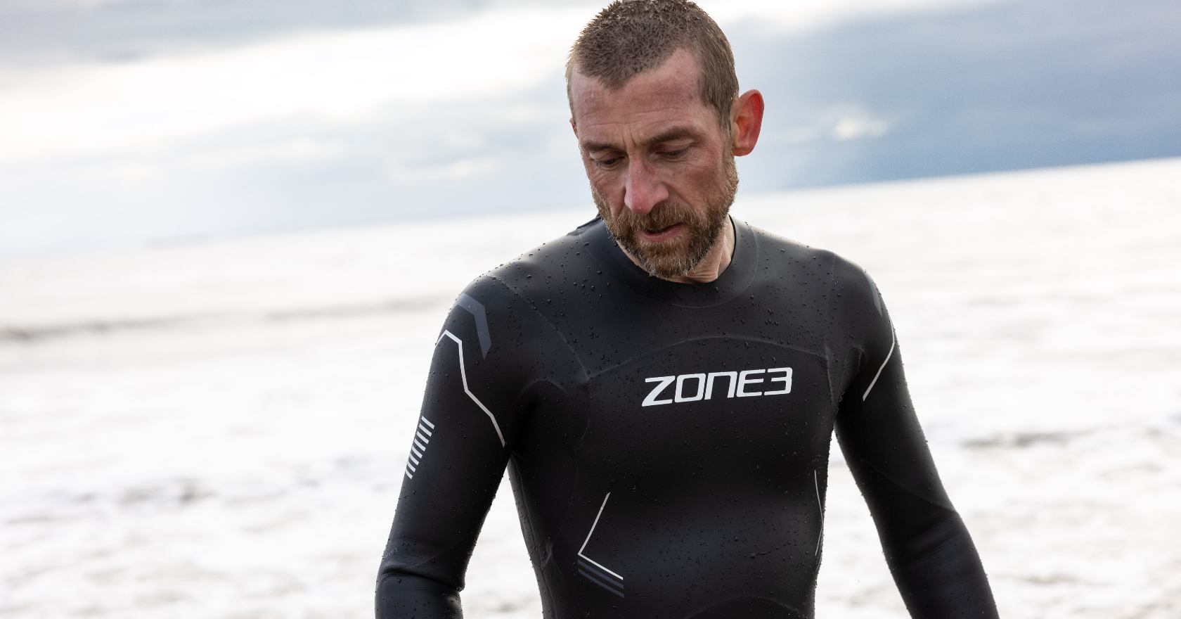 Zone 3 black wetsuit worn by man getting out of sea