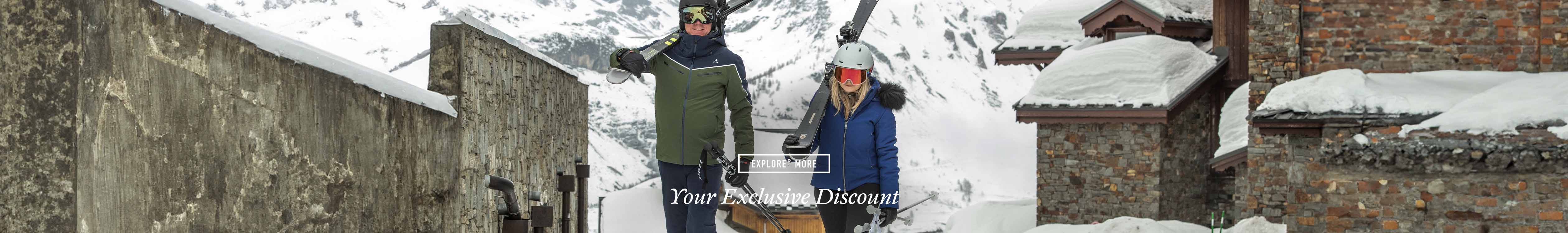£10 or £20 off your next order - Two people are carrying skis on their shoulders, wearing full ski gear