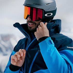 Shop men's ski gear. A man wearing a ski helmet and goggles in the snow