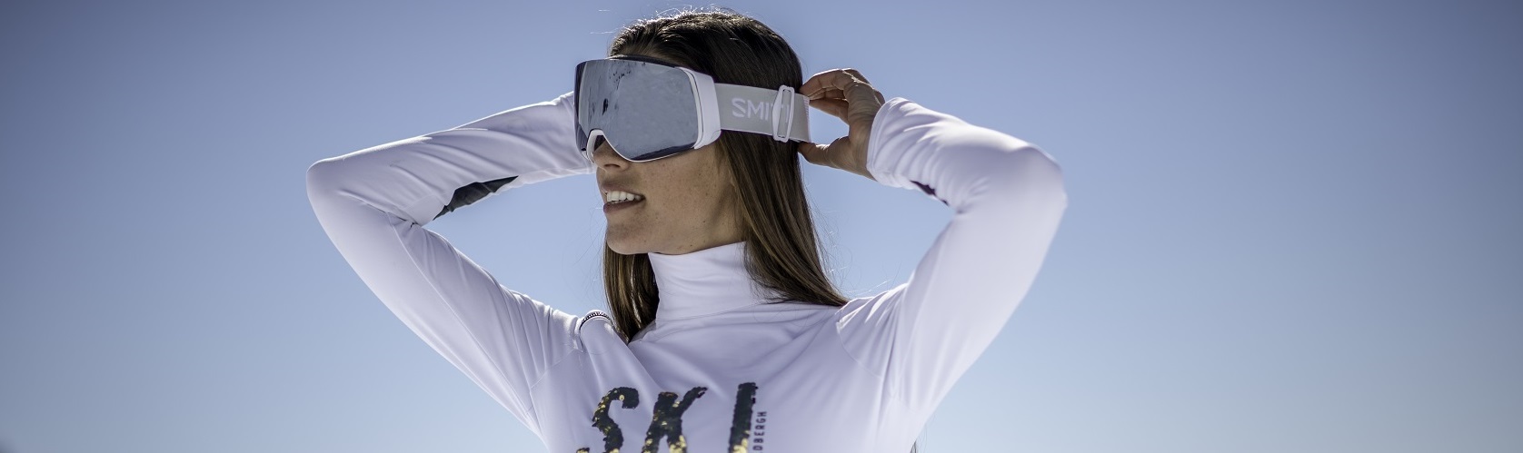 An image of a woman wearing a midlayer with goggles 