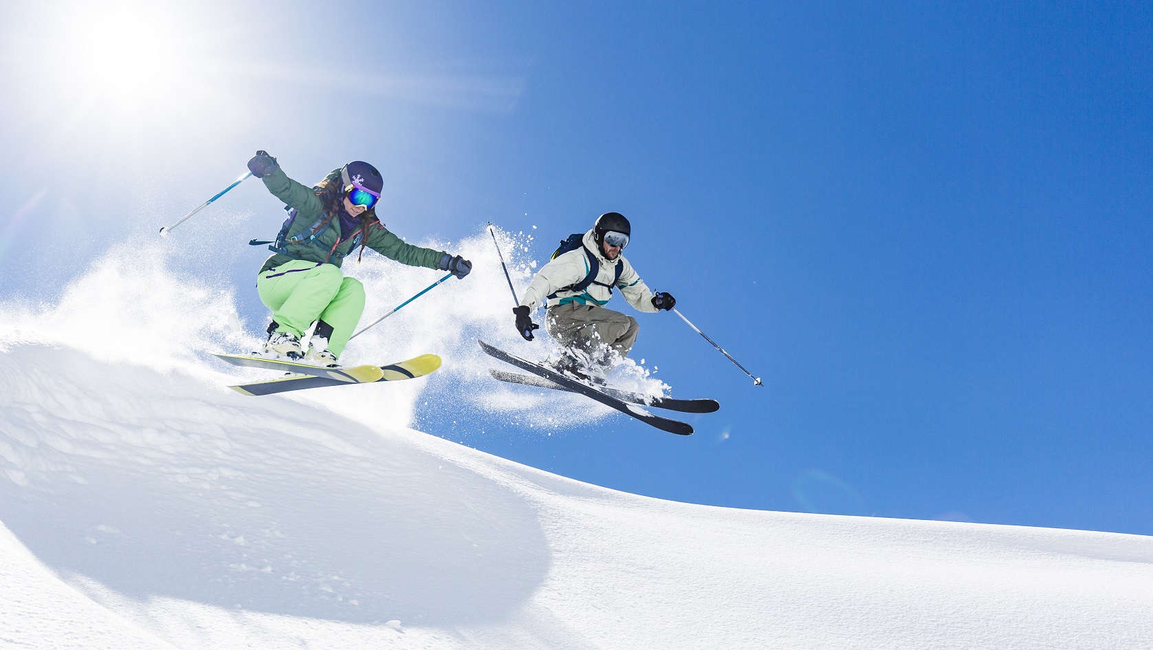 Young woman and man skiing and jumping in powder snow