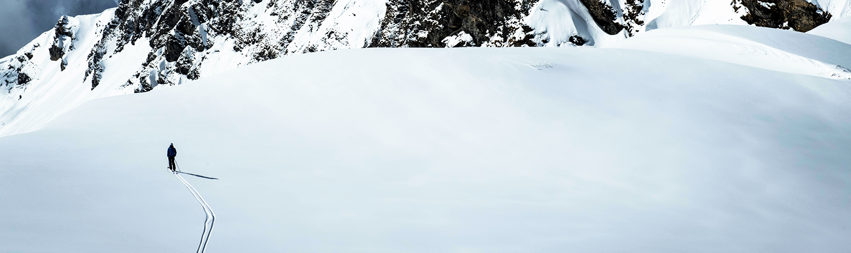 A person alpine touring through a snowy mountain environment 