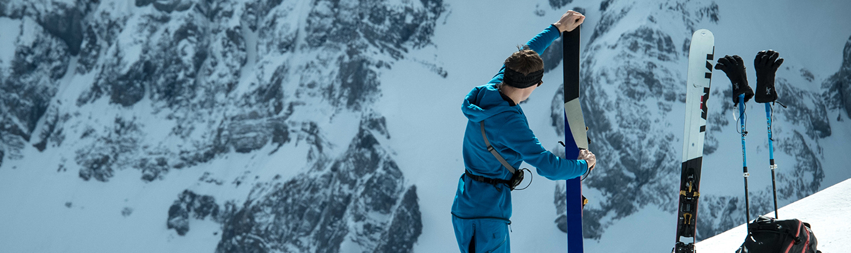 A person holding their AT skis 