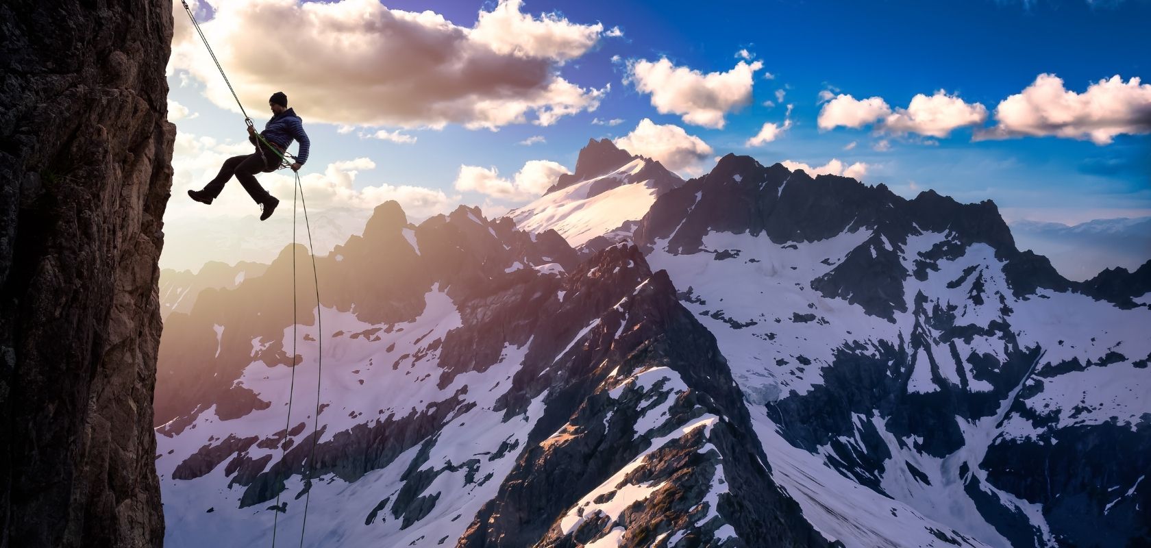 A person climbing with snowy mountains in the background 