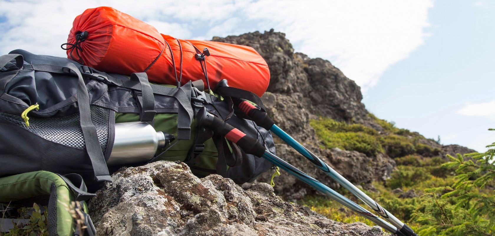 A rucksack with walking poles and sleeping bag attached 