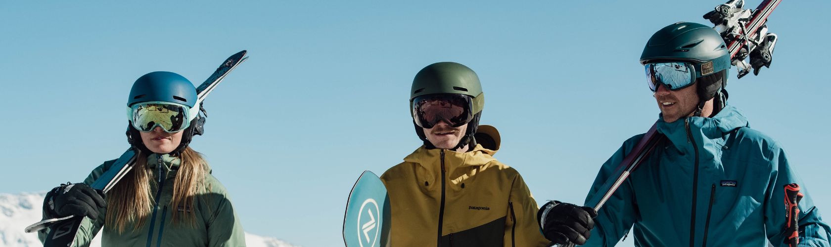 The men holding their skis wearing ski gear in the mountains