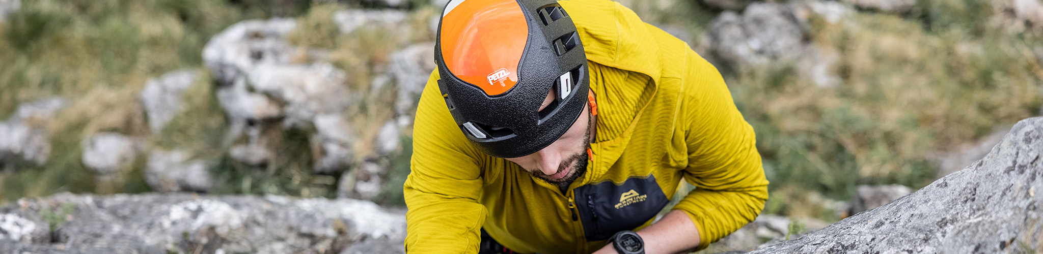 Shop climbing helmets. A man climbing on a rock