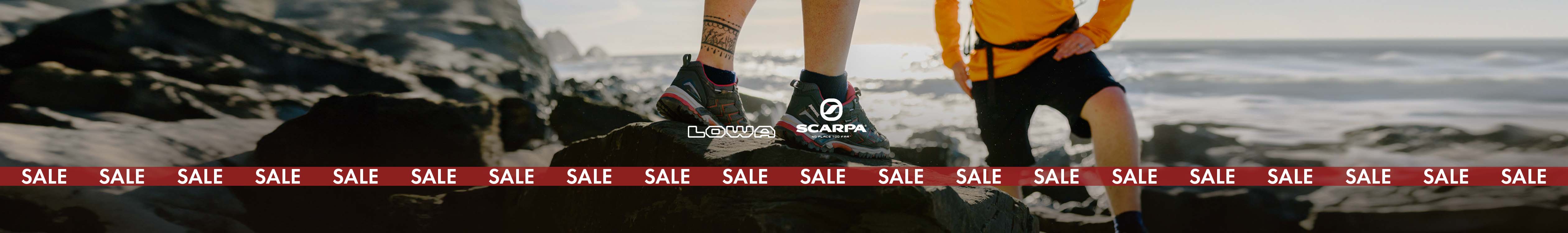 Footwear sale. Person's feet in walking shoes on a rocky beach by the sea