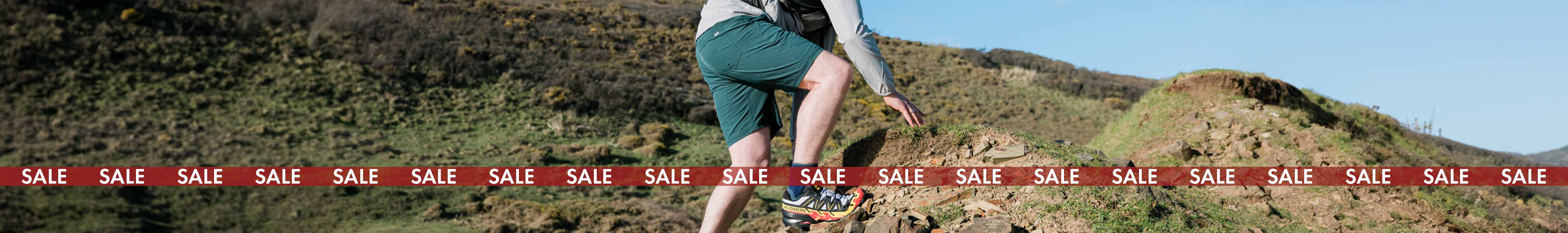 Men's sale. A man is by the sea, wearing t-shirt and shorts. 