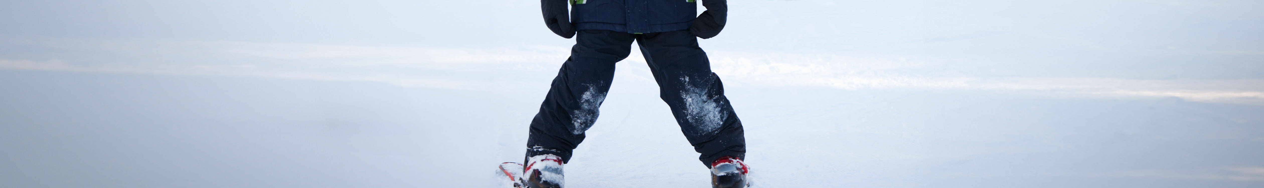 Shop Kid's leagwear. A kid standing on skies in dark blue ski pants