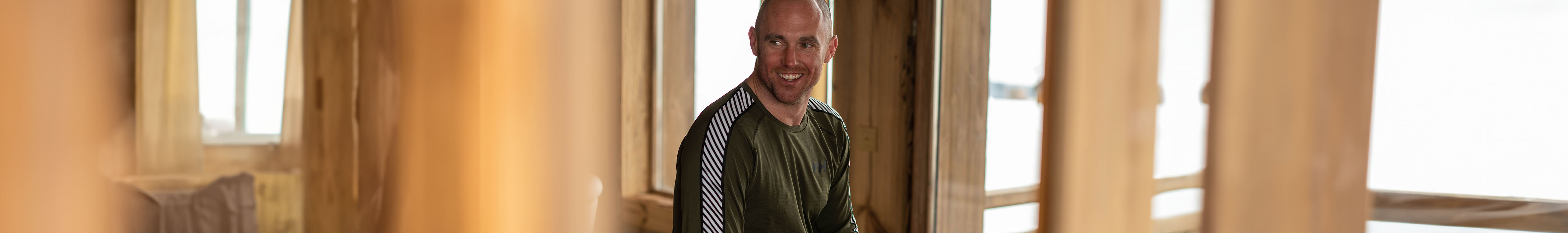 Shop mens baselayers. A man in a ski chalet wearing a baselayer