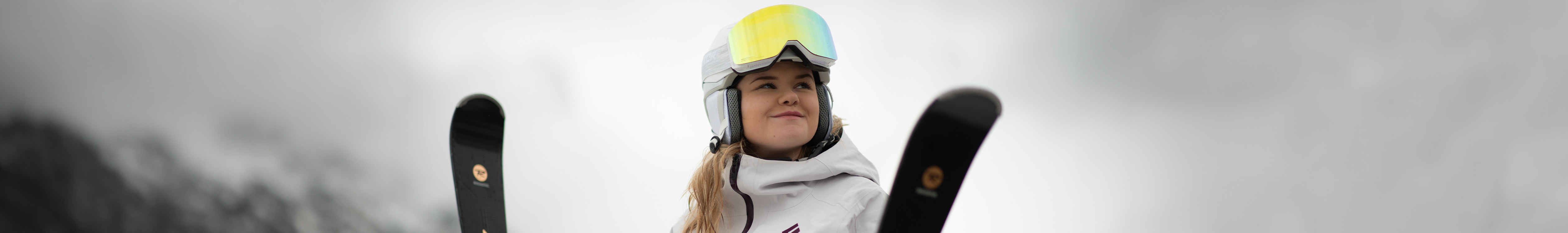 Shop ski goggles. A woman in white wearing helmet and ski goggles