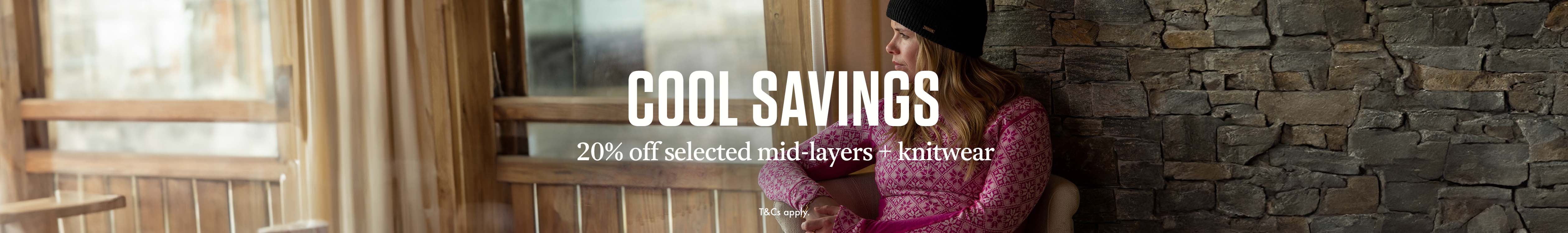 Cool Savings. 20% off selected midlayers + knitwear. A woman in a chalet wearing her merino fleece 