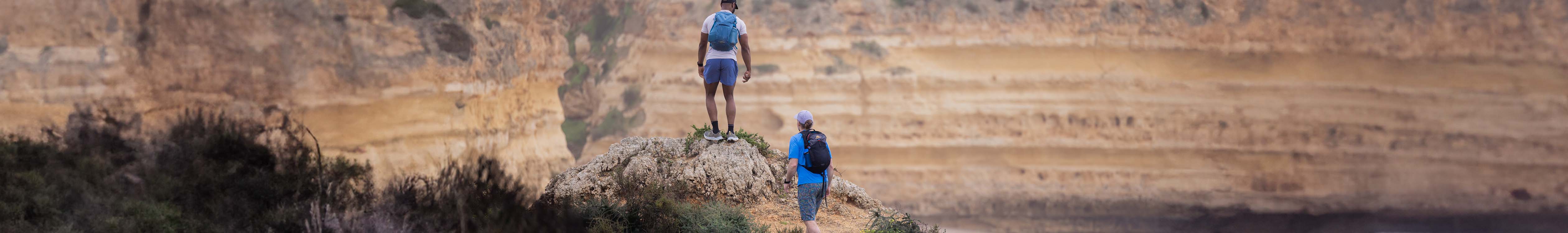 Shorts summer styles. Two men are hiking up, wearing t-shirts and shorts with backpacks somewhere warm