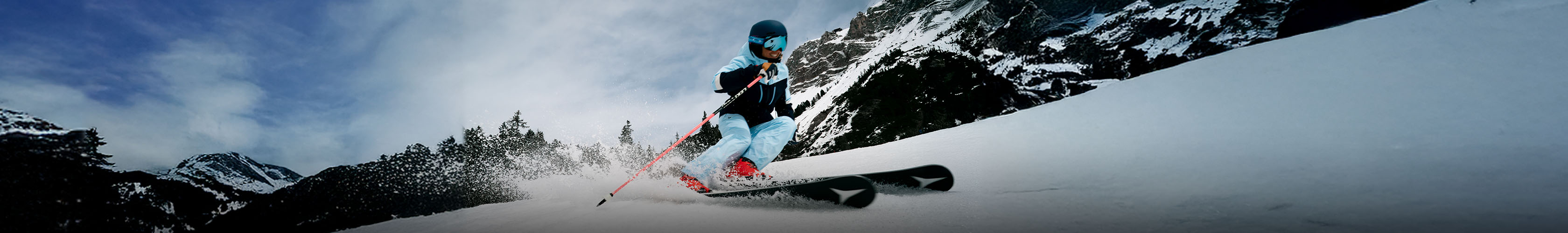 Shop ski new season. A person in yellow ski gear skiing down the mountain