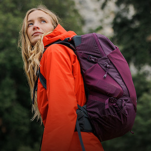 Shop packs + luggage. A woman in red jacket carrying purple backpack 