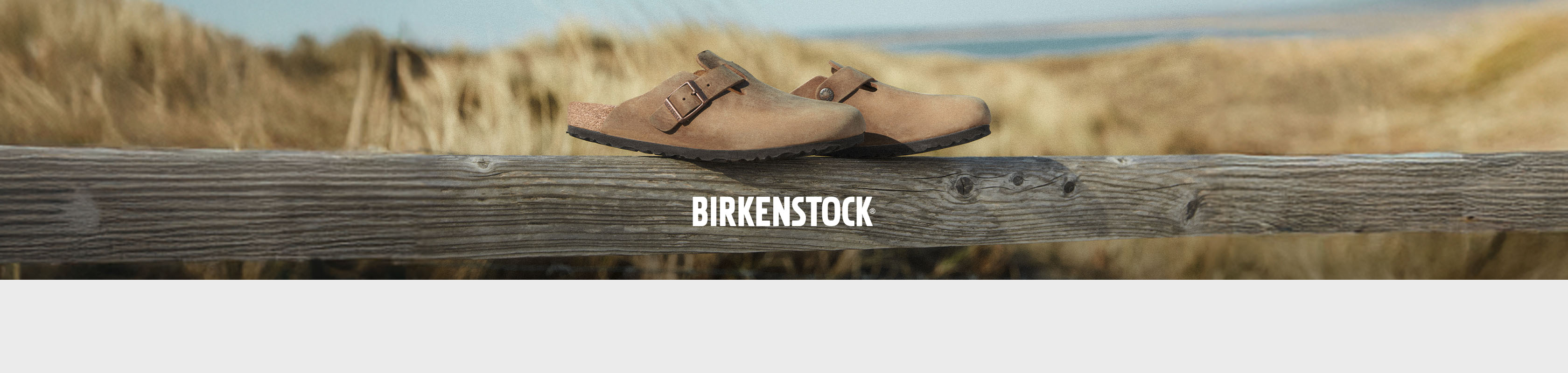 Shop Birkenstock collection. A pair of sliders on a wooden fence