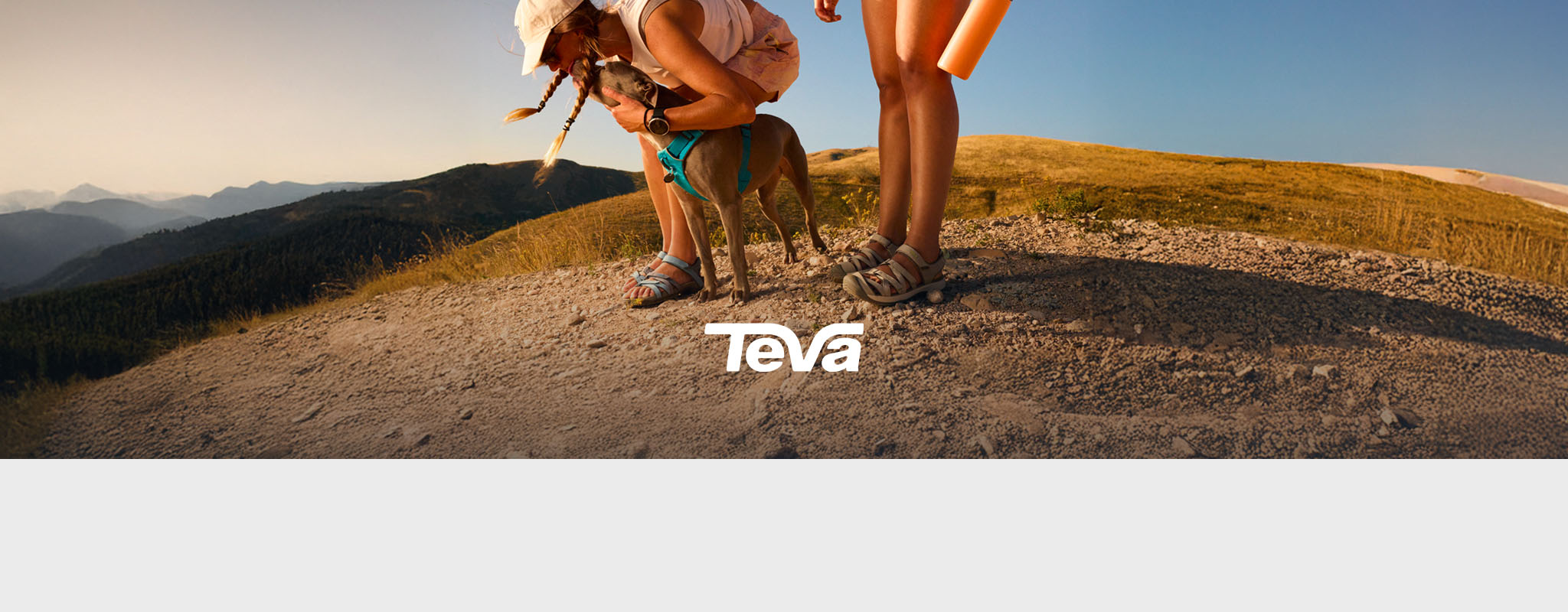 Shop Teva collection on Snow+Rock. Two people and a dog on a sandy dune