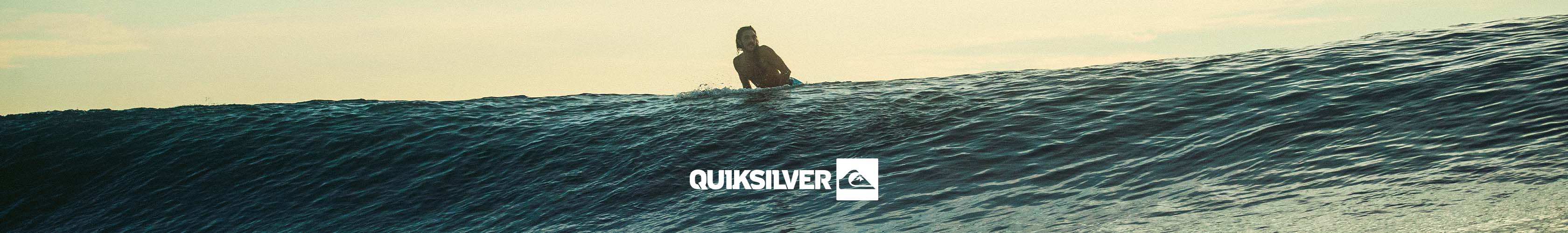 Shop Quicksilver clothing collection. A man surfing in the ocean