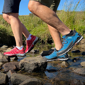 Shop trekking Footwear, People in red and blue walking shoes walking through a shallow stream