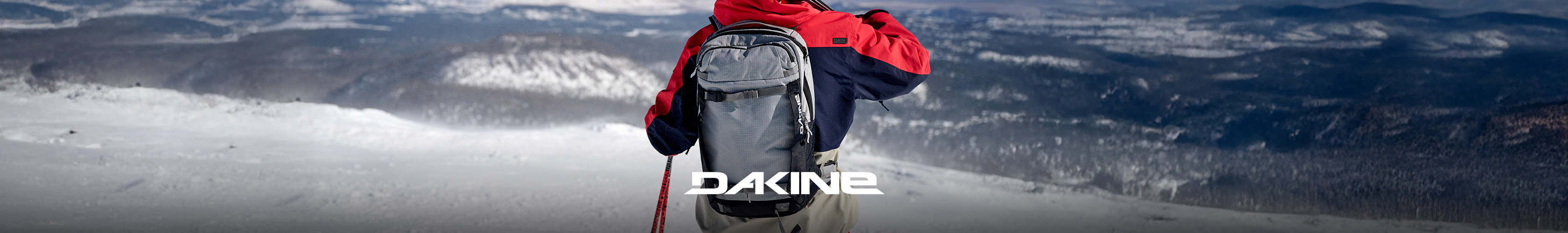 Shop Dakine collection. A person wearing backpack on a snowy mountain