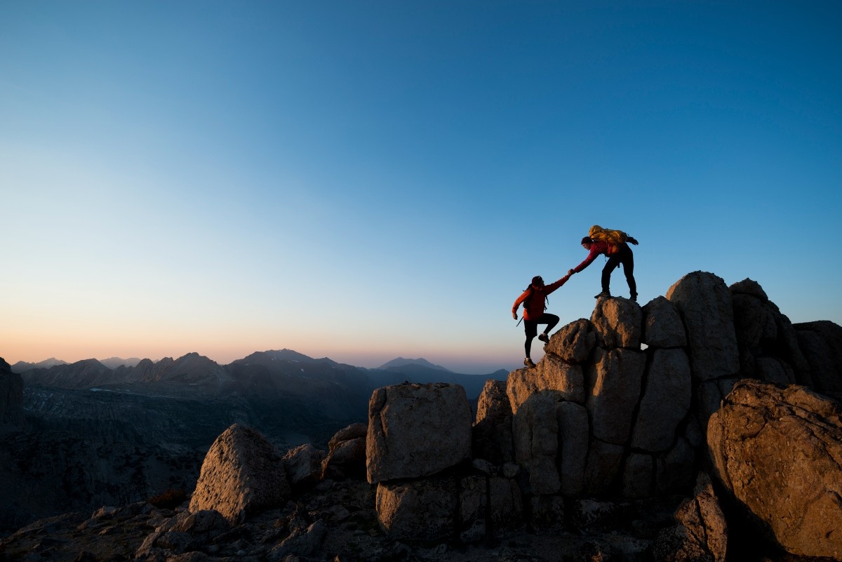 Two people climbing to a mountain's peak