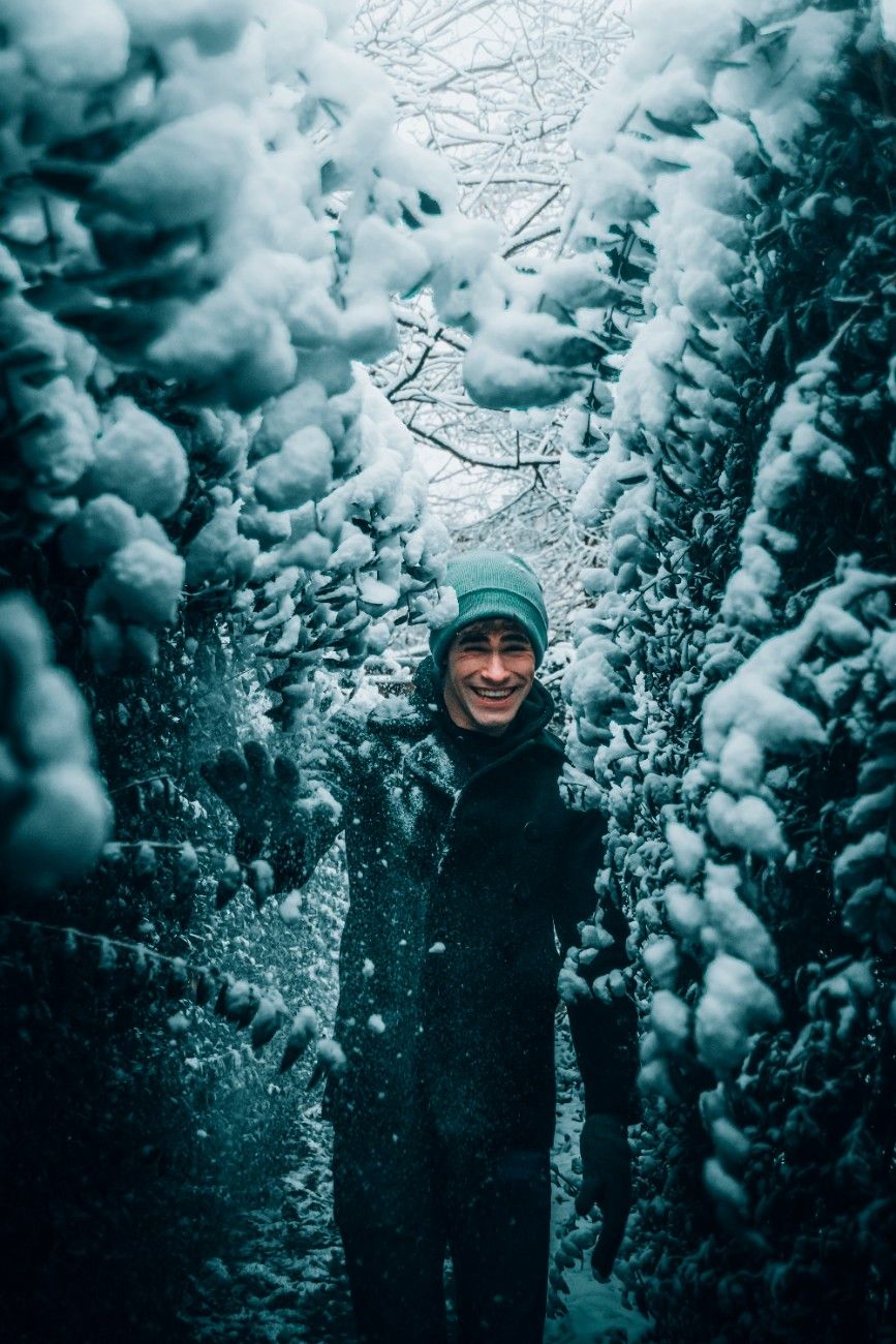 A man wearing a winter hat in a wintery forest 
