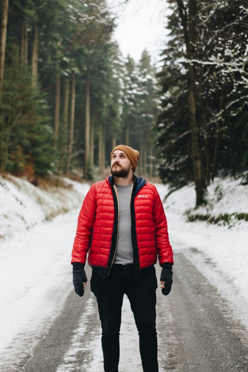 A man wearing a winter hat in a wintery forest 